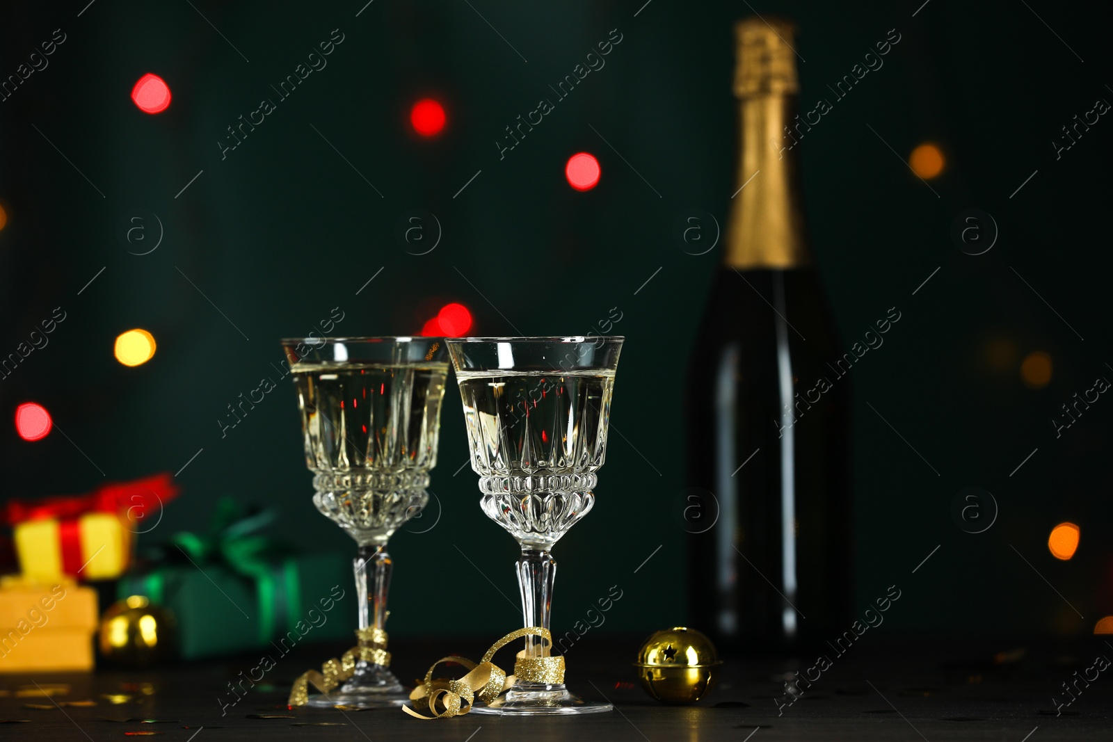 Photo of Glasses of sparkling wine on table against blurred lights