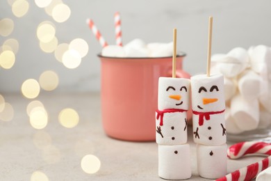 Photo of Funny snowmen made of marshmallows and other sweets on light table. Space for text