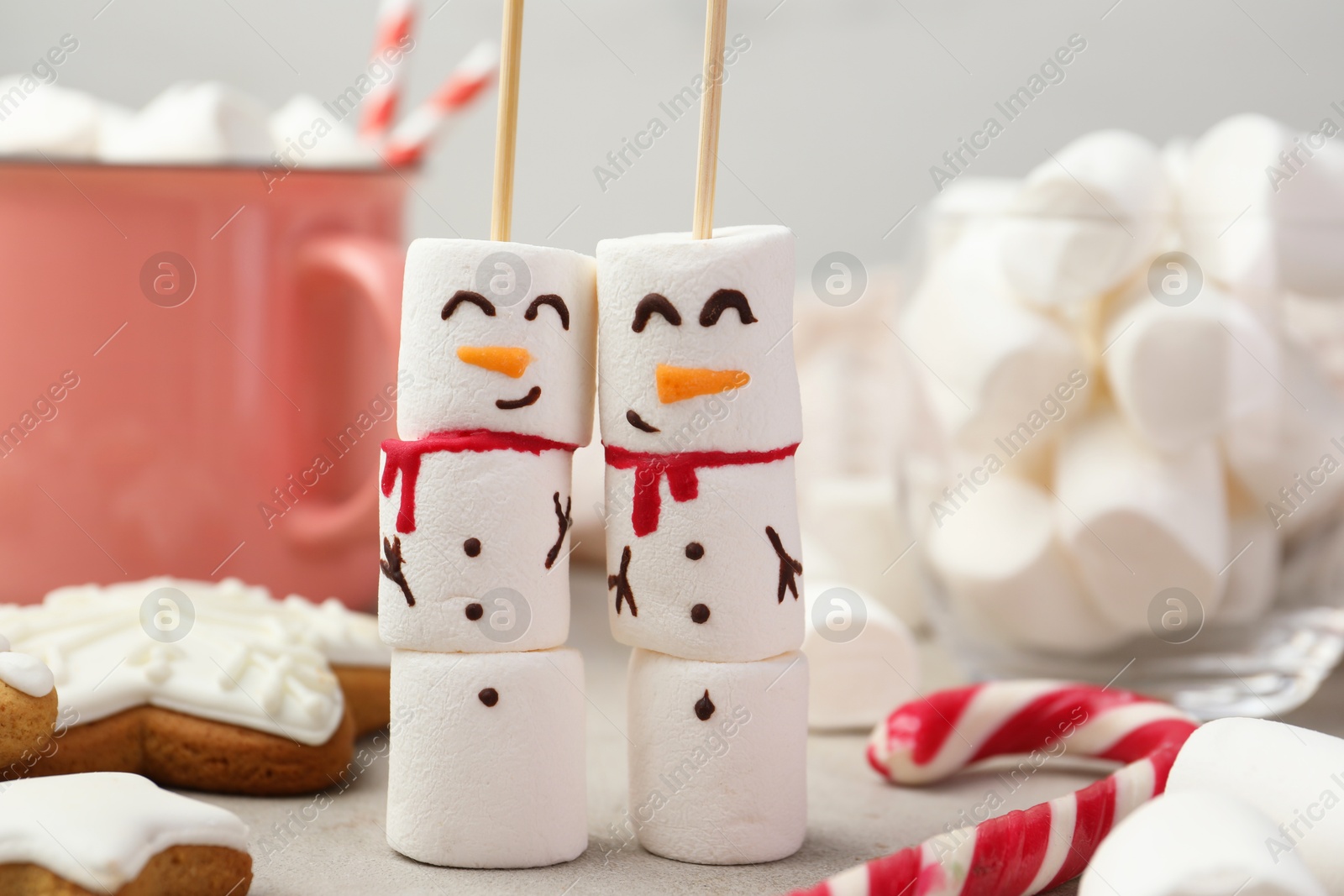 Photo of Funny snowmen made of marshmallows and other sweets on light table, closeup