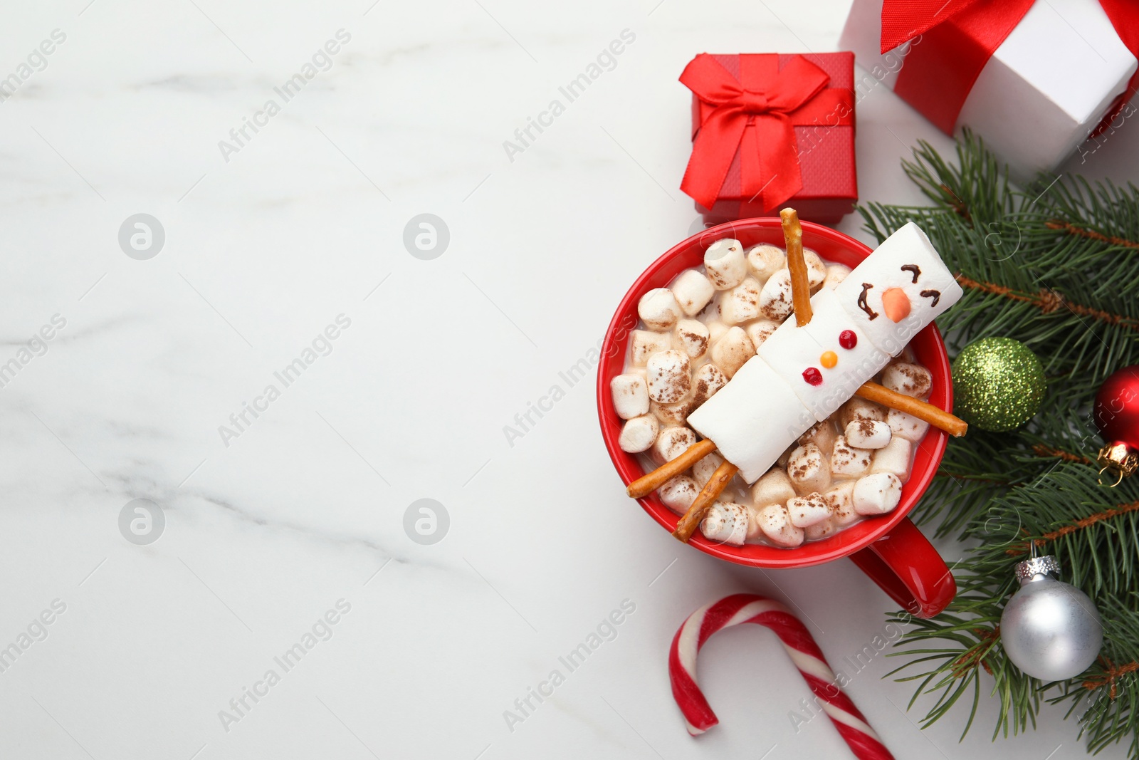 Photo of Funny snowman made with marshmallows in cup of hot drink and Christmas decor on white table, flat lay. Space for text