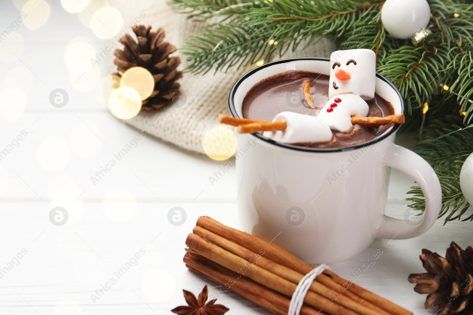 Photo of Funny snowman made with marshmallows in cup of hot chocolate and winter decor on white table