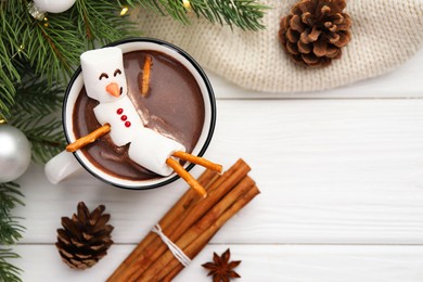 Photo of Funny snowman made with marshmallows in cup of hot chocolate and winter decor on white table, flat lay. Space for text