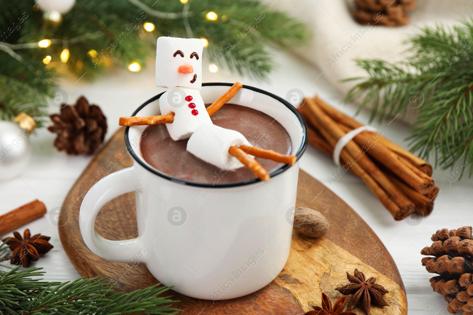 Photo of Funny snowman made with marshmallows in cup of hot chocolate and winter decor on white table