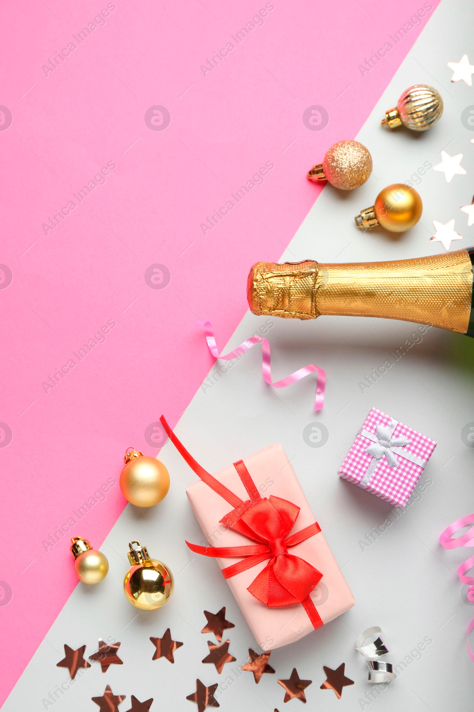 Photo of Flat lay composition with confetti and bottle of sparkling wine on color background, space for text. Christmas decor