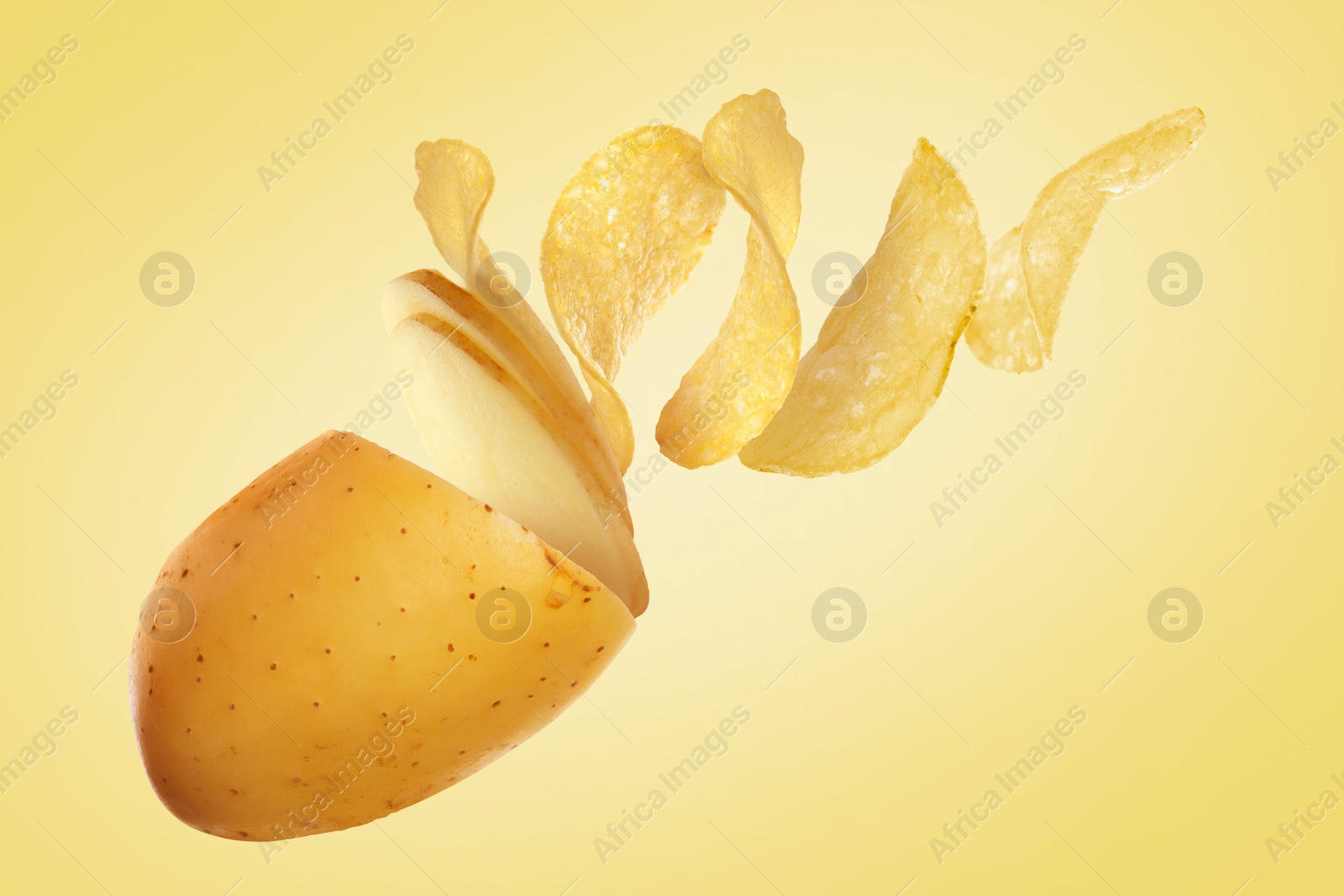 Image of Raw potato turning into tasty crispy chips in air on yellow background