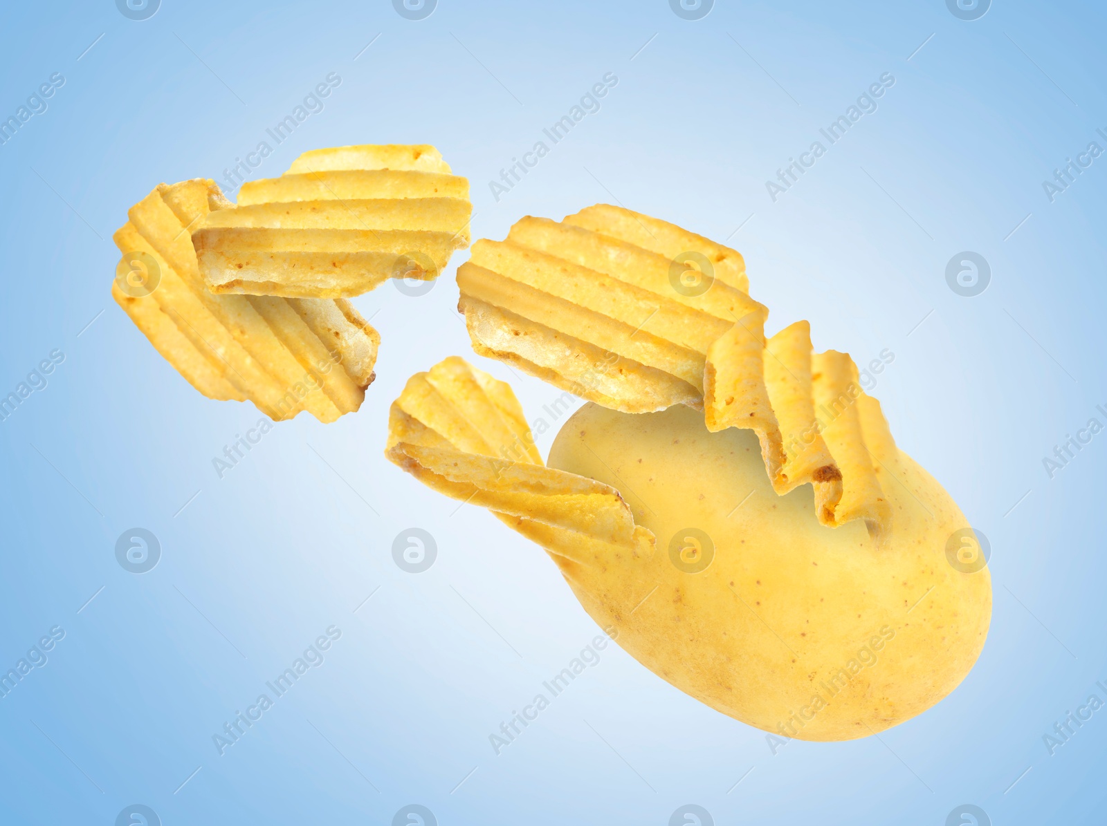 Image of Raw potato turning into tasty crispy chips in air on light blue gradient background