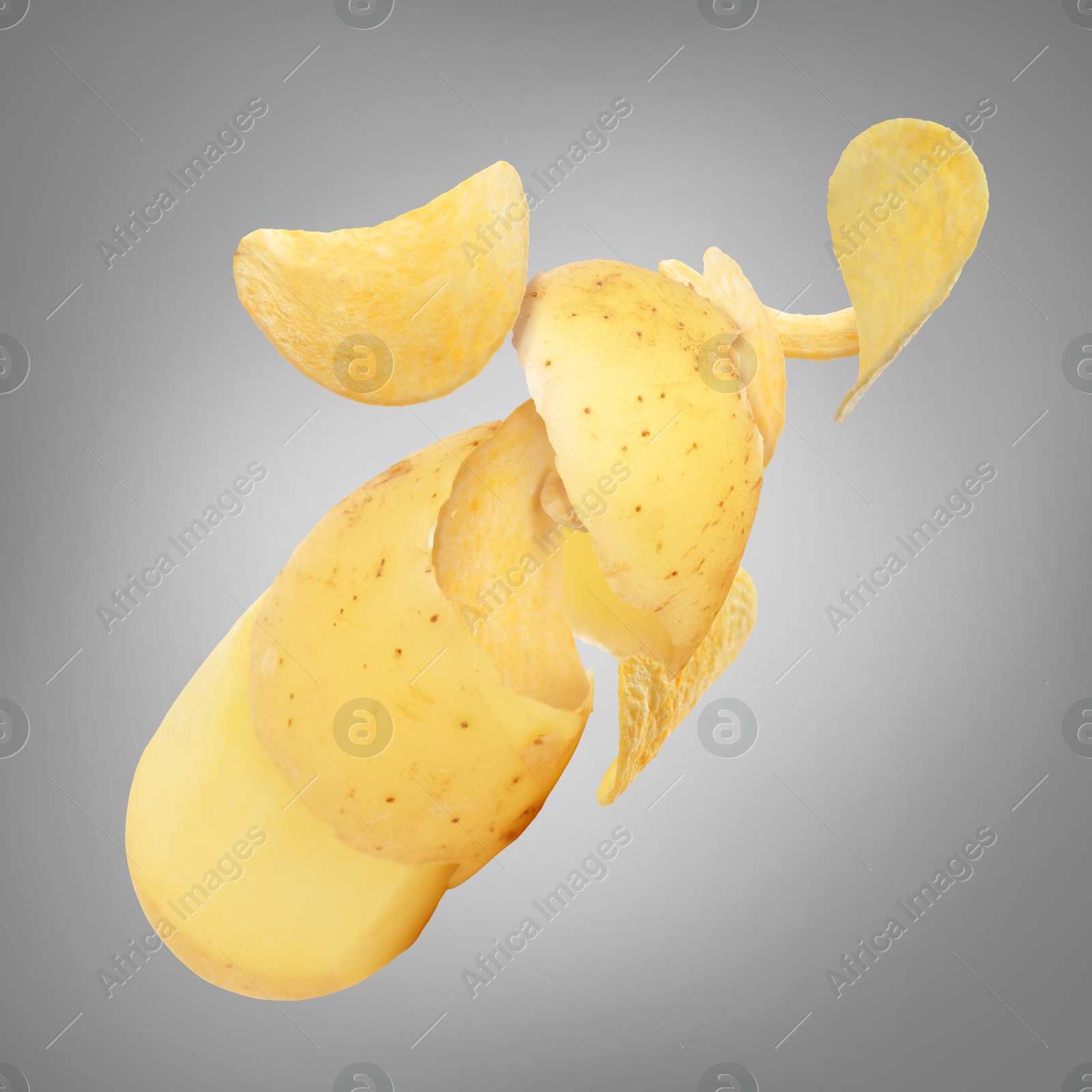 Image of Raw potato turning into tasty crispy chips in air on gray background