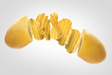 Image of Raw potato turning into tasty crispy chips in air on light background