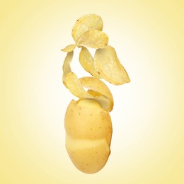 Image of Raw potato turning into tasty crispy chips in air on yellow gradient background