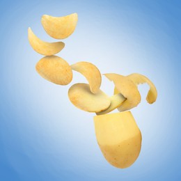 Image of Raw potato turning into tasty crispy chips in air on blue gradient background