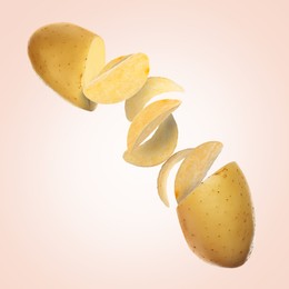 Image of Raw potato turning into tasty crispy chips in air on beige gradient background