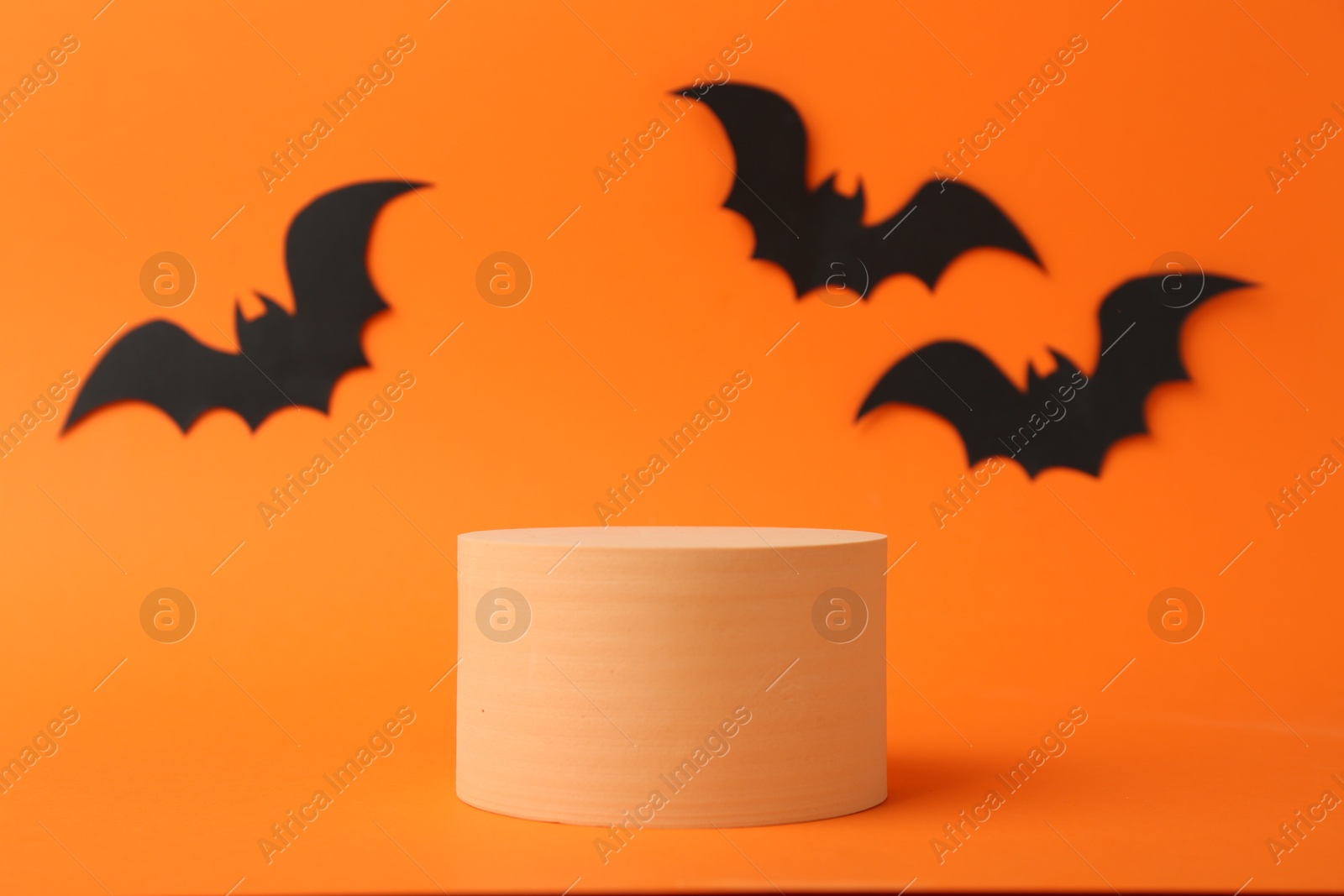 Photo of Halloween celebration. Black paper bats and podium on orange background