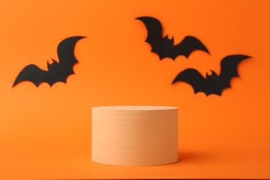 Photo of Halloween celebration. Black paper bats and podium on orange background