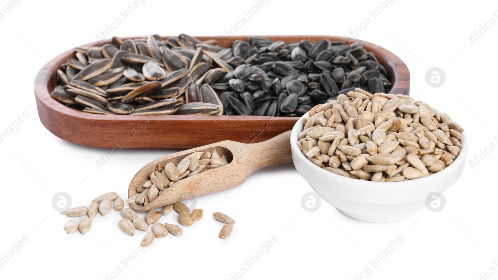 Photo of Different sunflower seeds, wooden plate, scoop and bowl isolated on white