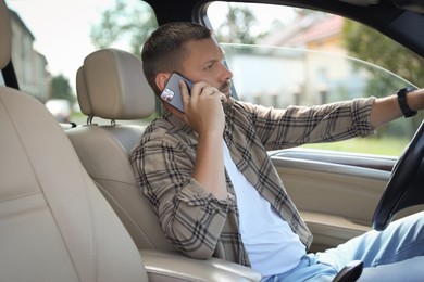 Photo of Man talking on smartphone while driving car