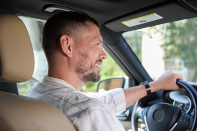 Photo of Happy man holding steering wheel while driving car