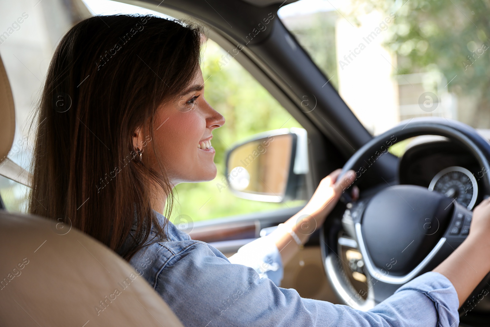 Photo of Smiling woman holding steering wheel while driving car