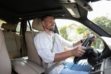 Photo of Smiling man holding steering wheel while driving car