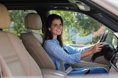 Smiling woman holding steering wheel while driving car