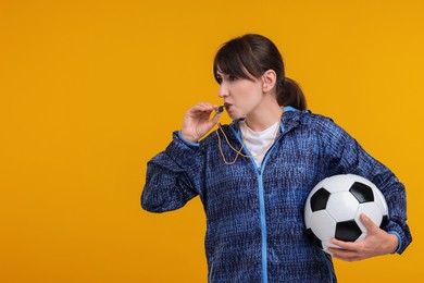 Photo of Woman with soccer ball blowing whistle on orange background, space for text