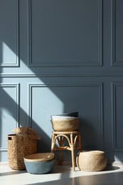 Photo of Stylish stool and many wicker baskets near light grey wall indoors, space for text