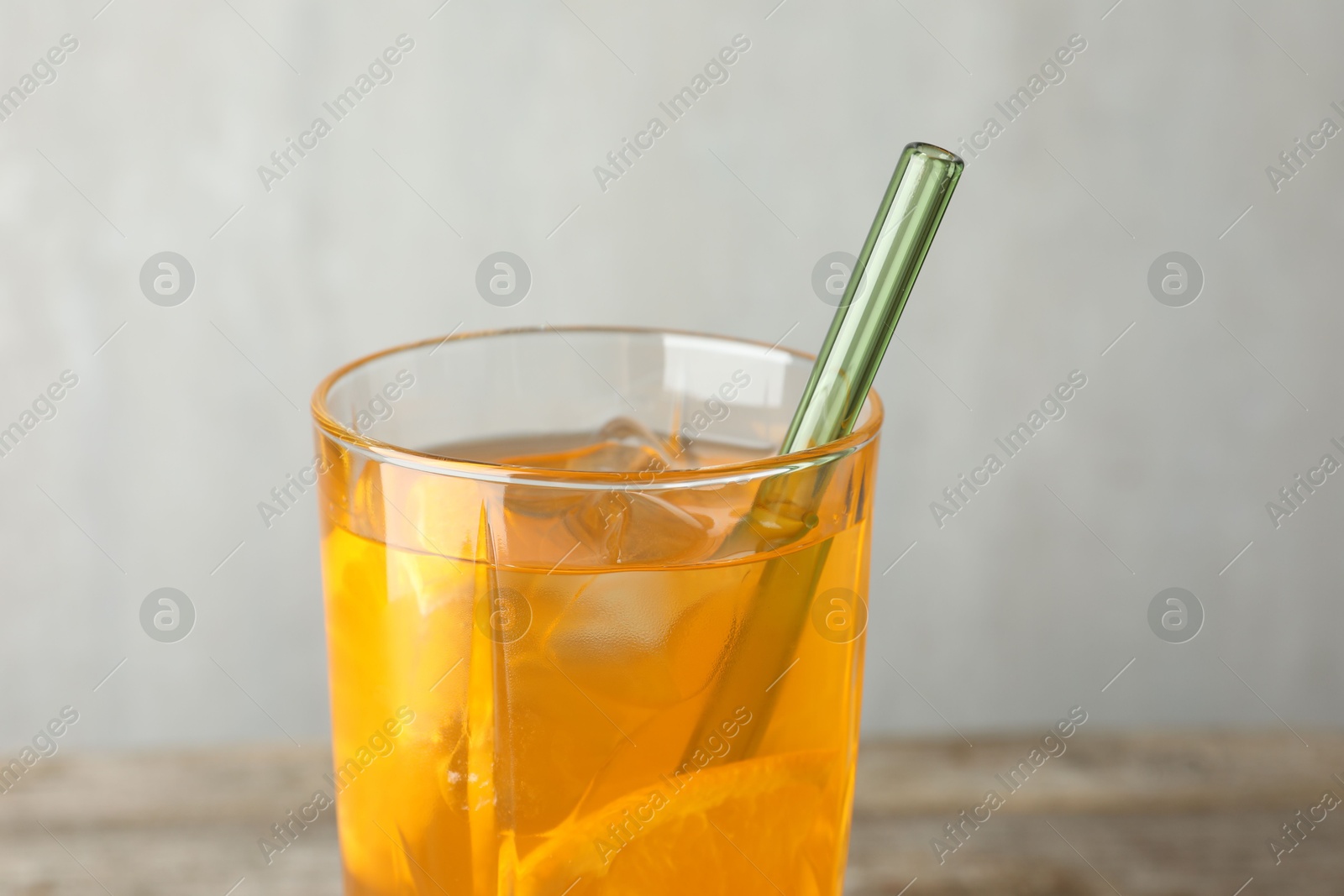 Photo of Glass of tasty refreshing drink and straw on table against gray background, closeup