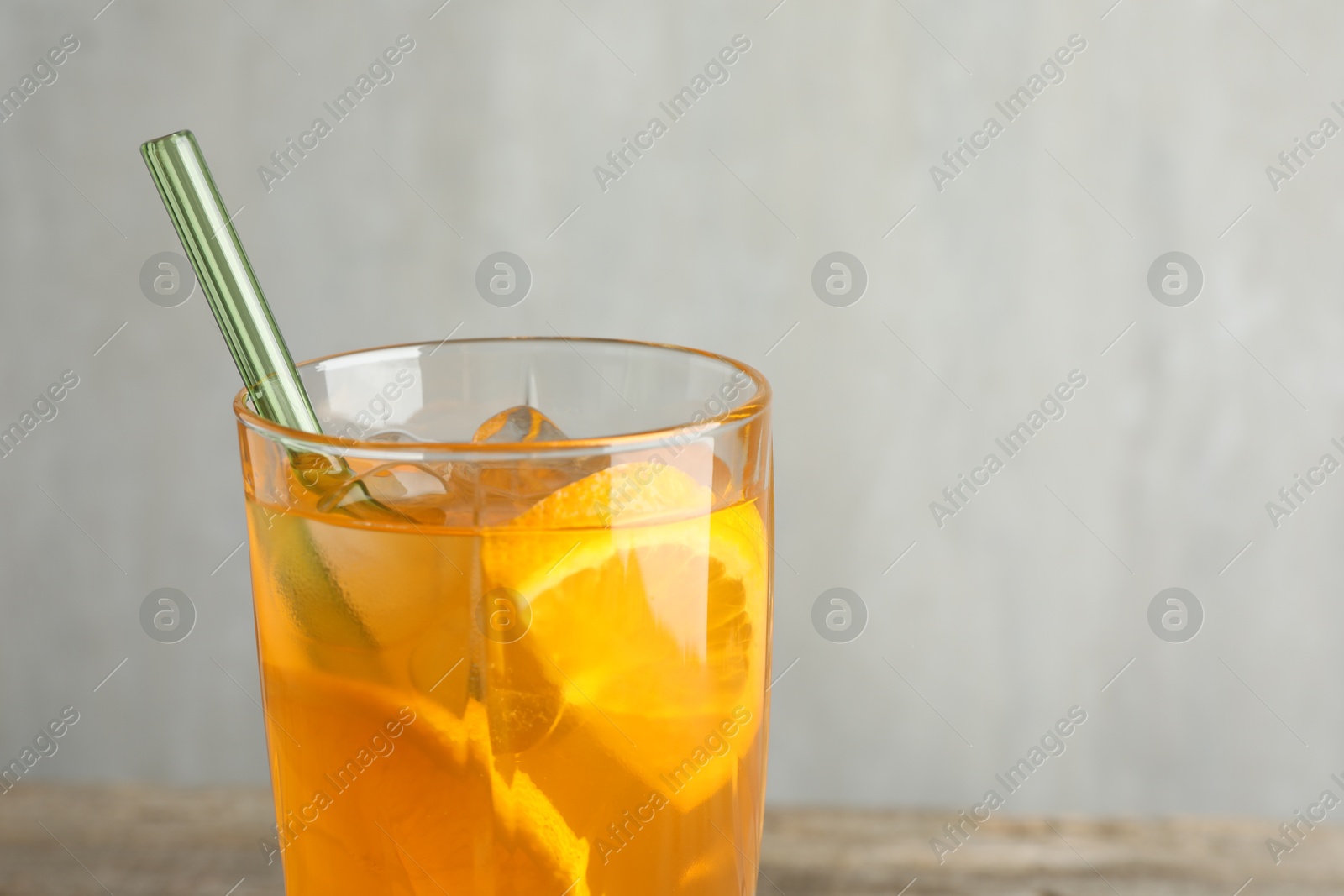 Photo of Glass of tasty refreshing drink and straw on table against gray background, closeup. Space for text