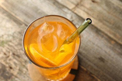 Glass of tasty refreshing drink and straw on wooden table, closeup