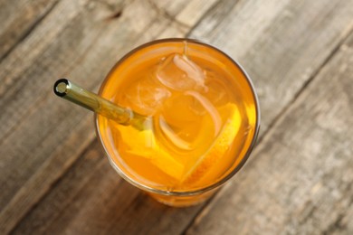 Glass of tasty refreshing drink and straw on wooden table, top view