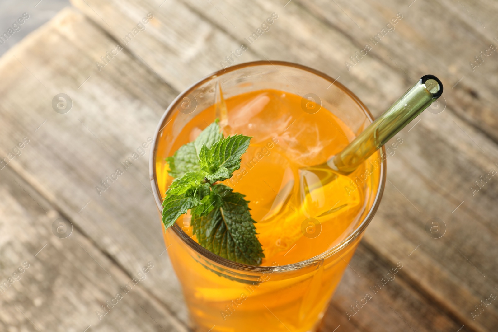 Photo of Glass of tasty refreshing drink and straw on wooden table, closeup