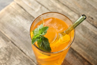 Glass of tasty refreshing drink and straw on wooden table, closeup