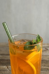 Photo of Glass of tasty refreshing drink and straw on table against gray background, closeup