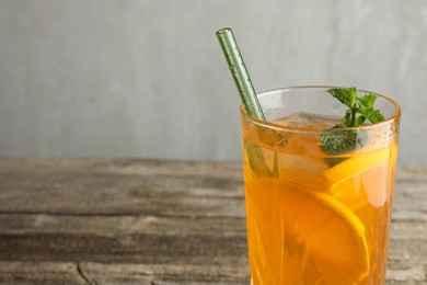 Photo of Glass of tasty refreshing drink and straw on wooden table against gray background, closeup. Space for text