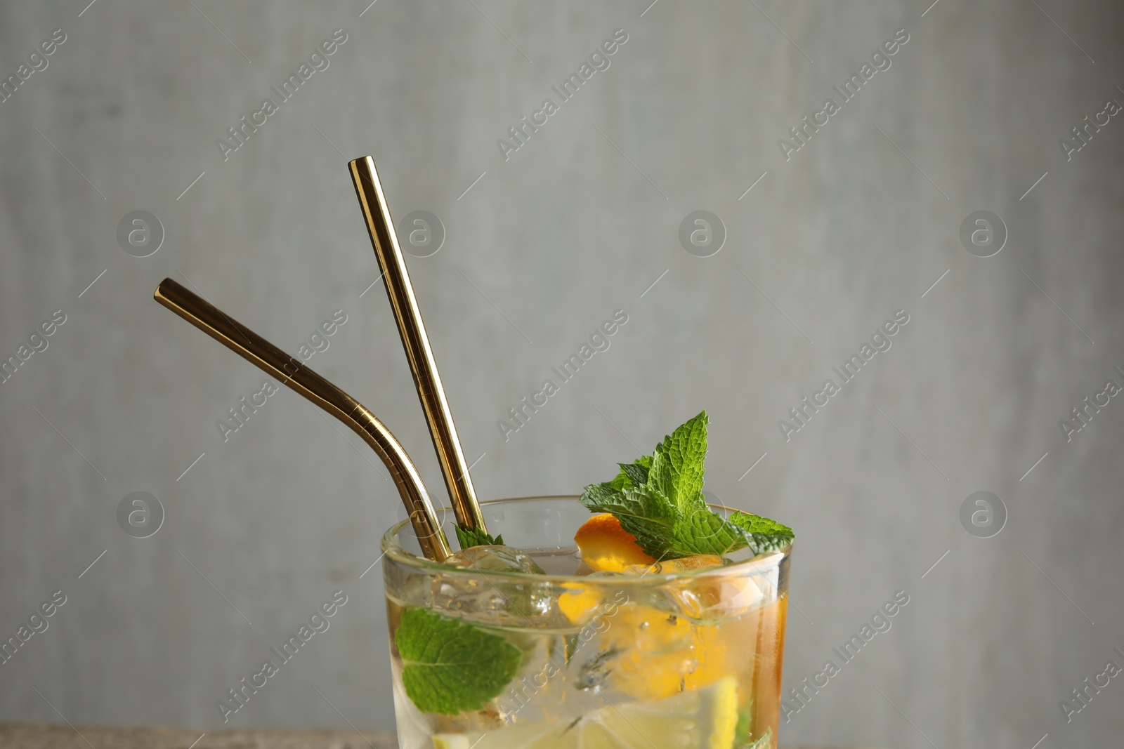 Photo of Glass of tasty refreshing drink and straws on gray background, closeup