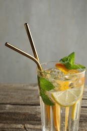 Photo of Glass of tasty refreshing drink and straws on wooden table against gray background, closeup