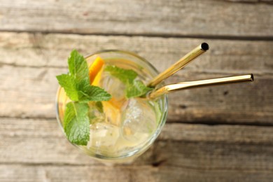 Photo of Glass of tasty refreshing drink and straws on wooden table, top view