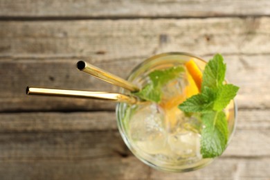 Photo of Glass of tasty refreshing drink and straws on wooden table, top view