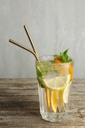 Photo of Glass of tasty refreshing drink and straws on wooden table against gray background