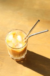 Photo of Glass of refreshing iced coffee and straws on wooden table outdoors, above view