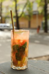 Photo of Glass of tasty refreshing drink and straw on table