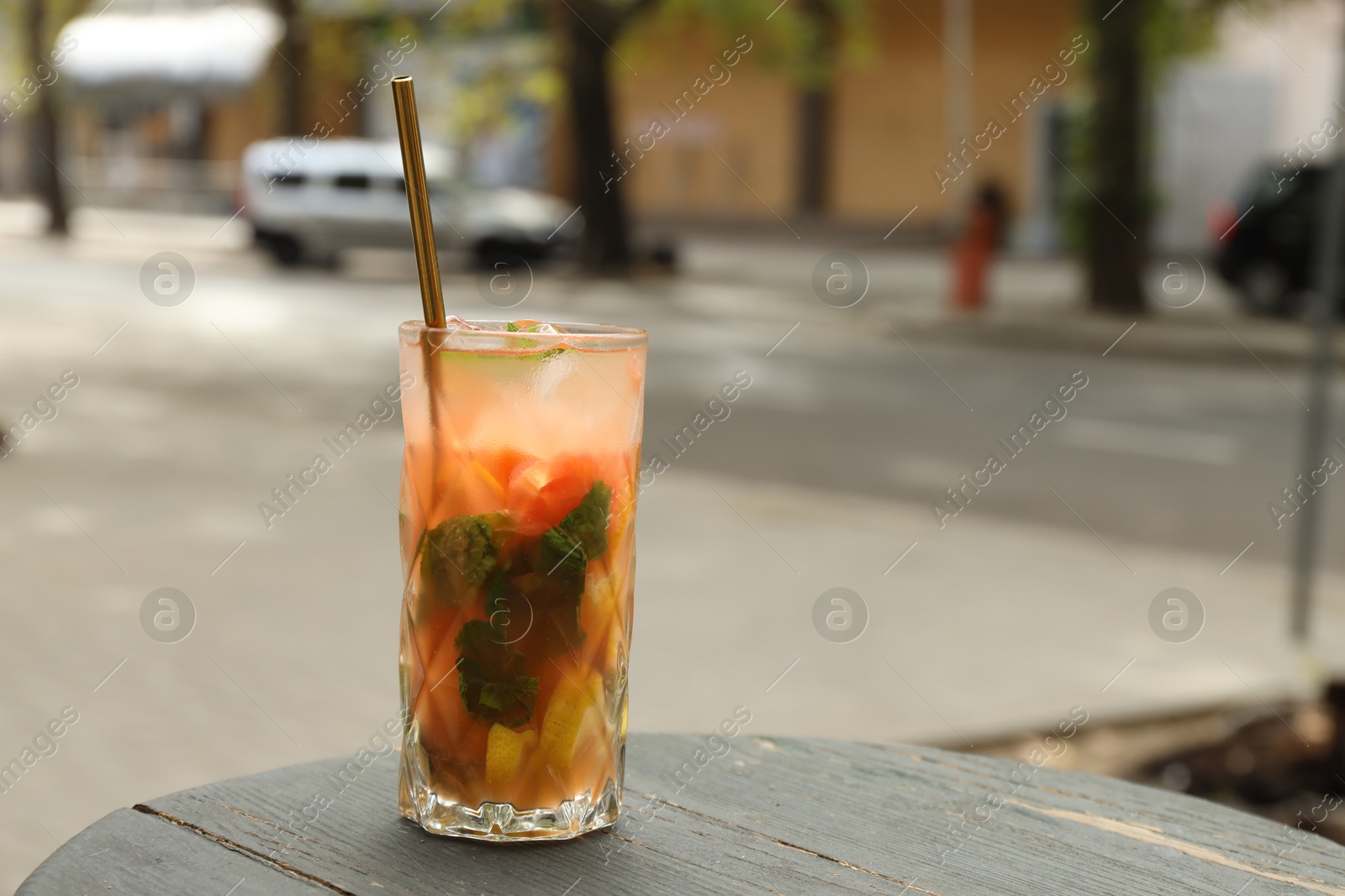 Photo of Glass of tasty refreshing drink and straw on table