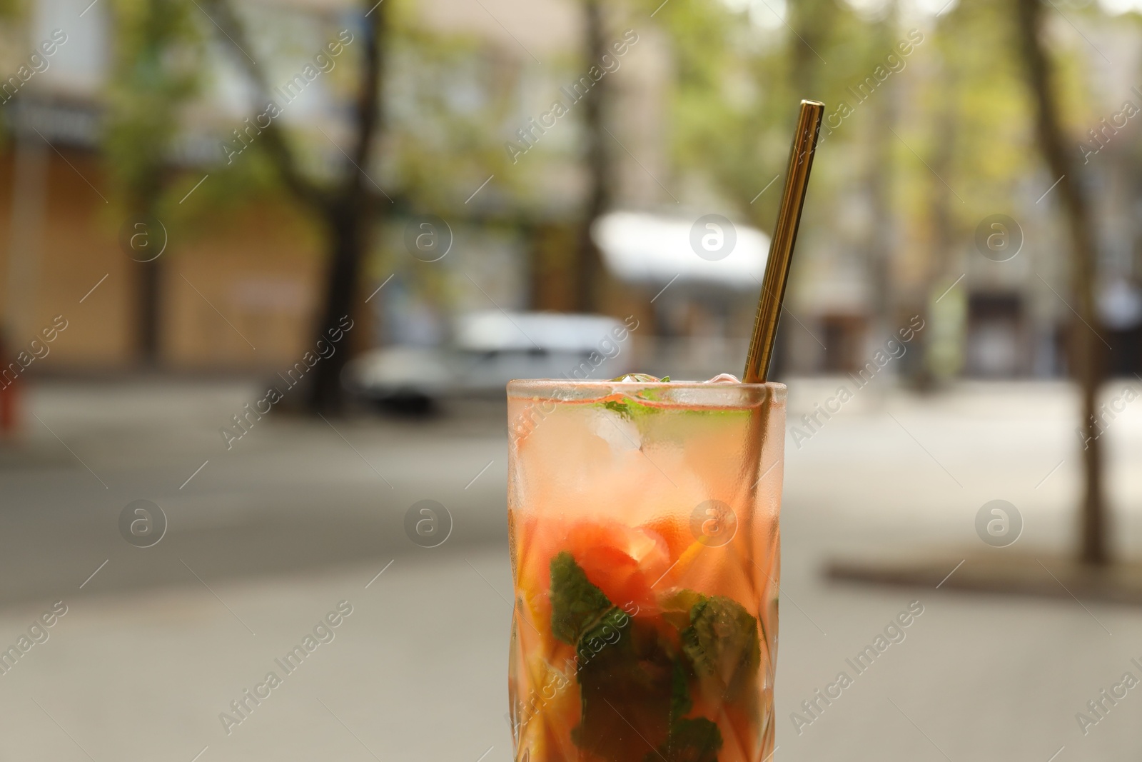 Photo of Glass of tasty refreshing drink and straw outdoors, closeup