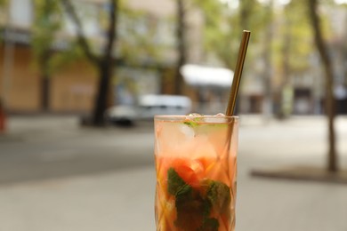 Photo of Glass of tasty refreshing drink and straw outdoors, closeup