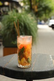 Photo of Glass of tasty refreshing drink and straws on wooden table