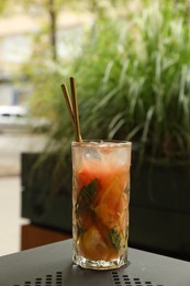 Photo of Glass of tasty refreshing drink and straws on table