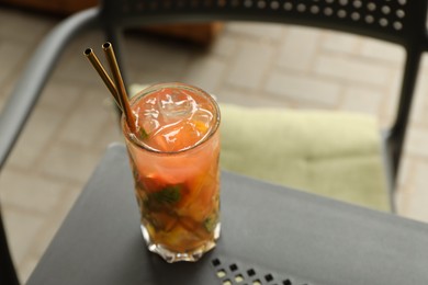 Photo of Glass of tasty refreshing drink and straws on table, closeup