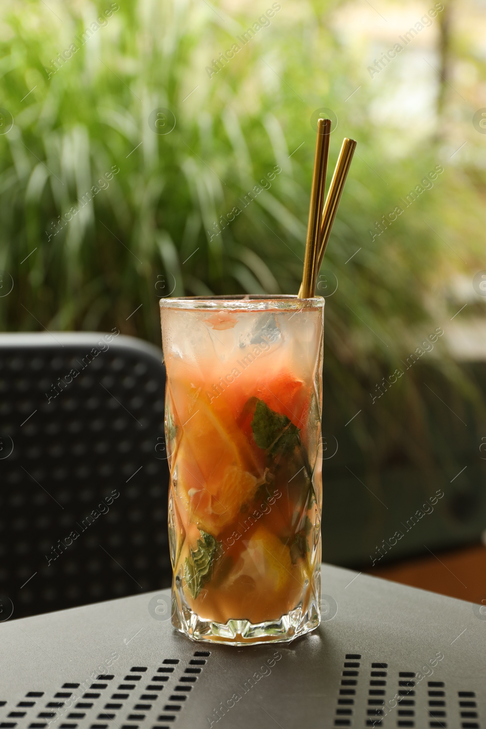 Photo of Glass of tasty refreshing drink and straws on table