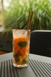 Photo of Glass of tasty refreshing drink and straws on table in outdoor cafe