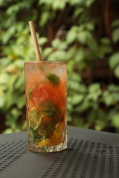 Glass of tasty refreshing drink and straw on table in outdoor cafe