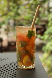 Photo of Glass of tasty refreshing drink and straw on table in outdoor cafe